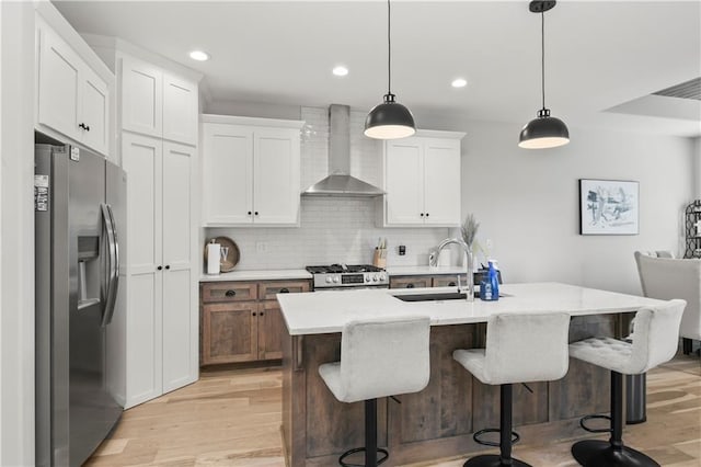 807 NE Algonquin St Unit B, Lees Summit, MO 64064 - kitchen featuring stainless steel appliances, wall chimney exhaust hood, light wood-type flooring, tasteful backsplash, and white cabinets