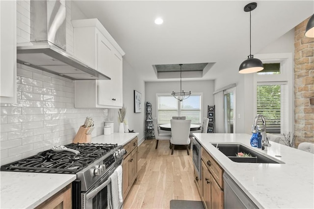 807 NE Algonquin St Unit B, Lees Summit, MO 64064 - kitchen with wall chimney range hood, stainless steel appliances, a sink, a raised ceiling, and light wood finished floors