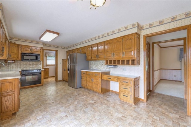 25908 Colbern Rd, Lees Summit, MO 64086 - kitchen featuring wallpapered walls, black appliances, light countertops, brown cabinetry, and a sink