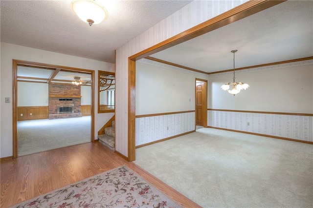 25908 Colbern Rd, Lees Summit, MO 64086 - carpeted spare room featuring wallpapered walls, wainscoting, a brick fireplace, stairway, and a chandelier