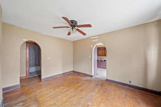 1111 S Cottage St, Independence, MO 64050 - unfurnished room featuring arched walkways, ceiling fan, wood finished floors, and baseboards