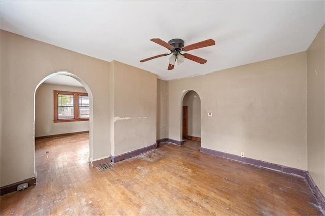 1111 S Cottage St, Independence, MO 64050 - unfurnished room with arched walkways, a ceiling fan, wood finished floors, and baseboards