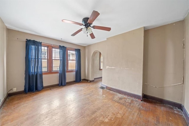 1111 S Cottage St, Independence, MO 64050 - spare room with ceiling fan, hardwood / wood-style flooring, arched walkways, and baseboards