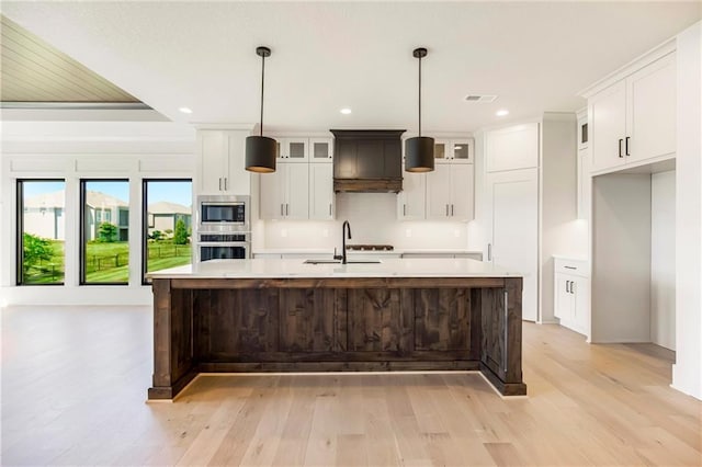 17556 Acton St, Overland Park, KS 66085 - kitchen with appliances with stainless steel finishes, a sink, light wood-style flooring, light countertops, and a spacious island