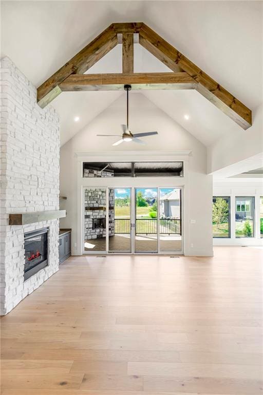 17556 Acton St, Overland Park, KS 66085 - unfurnished living room featuring a stone fireplace, a ceiling fan, high vaulted ceiling, beamed ceiling, and wood finished floors
