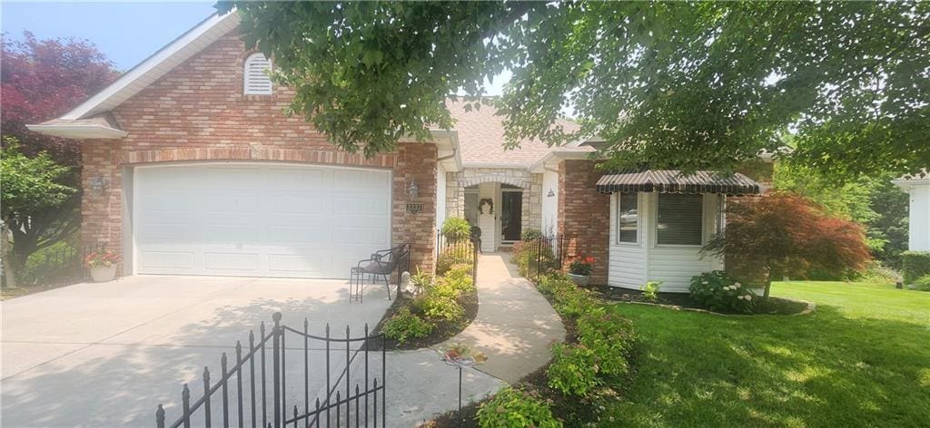 3337 S Victoria Dr, Blue Springs, MO 64015 - view of front of property with concrete driveway, a front yard, a garage, and brick siding