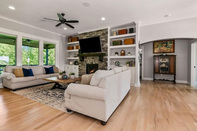 9305 SW Sushi Cir, Lees Summit, MO 64064 - living room with arched walkways, crown molding, a ceiling fan, light wood finished floors, and a fireplace