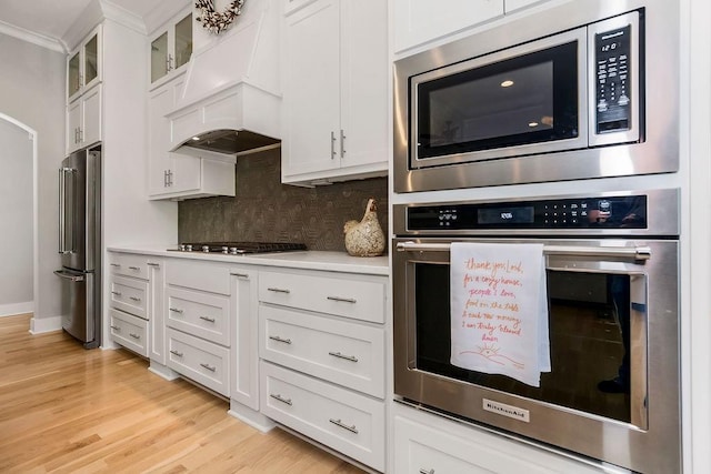 9305 SW Sushi Cir, Lees Summit, MO 64064 - kitchen with appliances with stainless steel finishes, custom range hood, light countertops, backsplash, and white cabinets