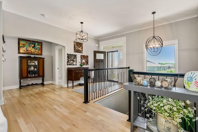 9305 SW Sushi Cir, Lees Summit, MO 64064 - hallway featuring a chandelier, an upstairs landing, light wood-style flooring, arched walkways, and ornamental molding