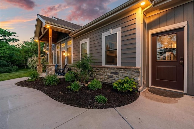 9425 NE 188th St, Trimble, MO 64492 - exterior entry at dusk with stone siding and covered porch