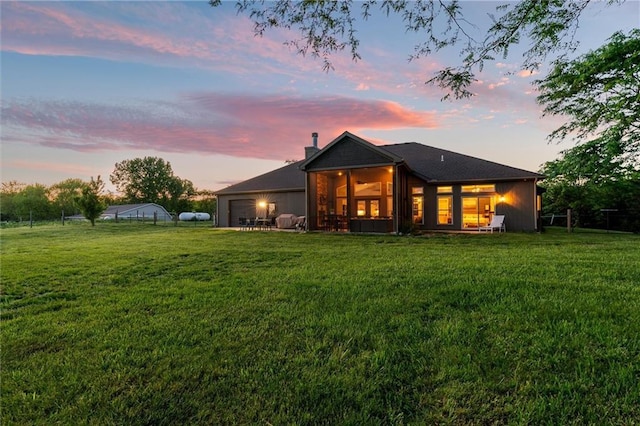 9425 NE 188th St, Trimble, MO 64492 - rear view of property featuring a sunroom, a lawn, a chimney, and a garage