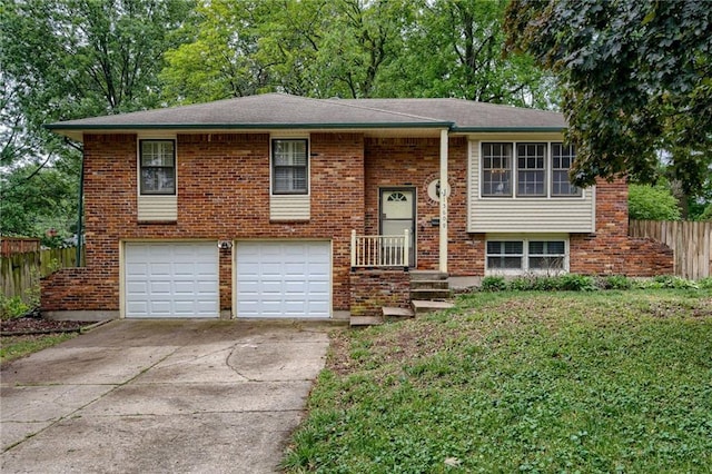 15609 E 43rd St S, Independence, MO 64055 - raised ranch featuring a garage, concrete driveway, brick siding, and view of scattered trees