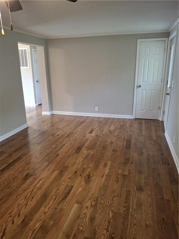 715 E Blackhawk St, Ottawa, KS 66067 - unfurnished room with ornamental molding, a ceiling fan, dark wood-style floors, and baseboards
