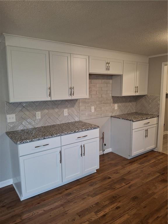 715 E Blackhawk St, Ottawa, KS 66067 - kitchen with dark stone countertops, white cabinetry, a textured ceiling, decorative backsplash, and dark wood-type flooring
