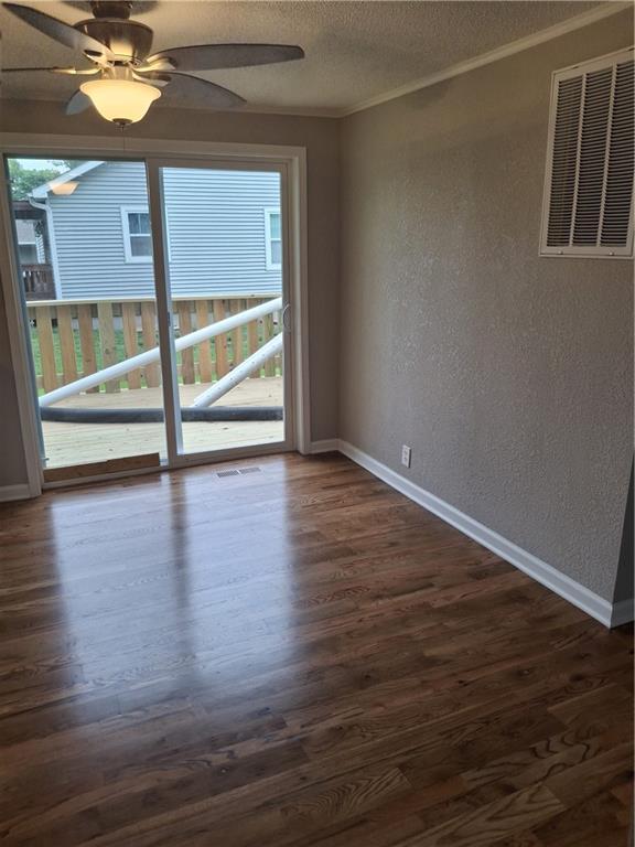 715 E Blackhawk St, Ottawa, KS 66067 - empty room featuring a textured wall, plenty of natural light, dark wood finished floors, crown molding, and baseboards