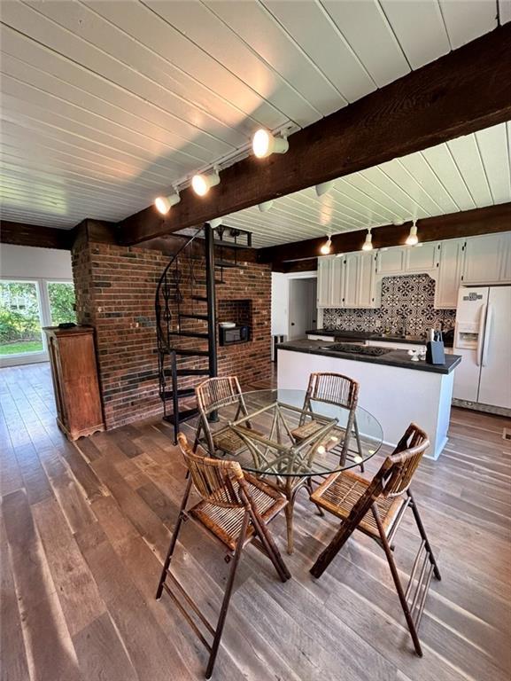 1702 Countryside Dr, Pittsburg, KS 66762 - dining space featuring brick wall, track lighting, a fireplace, and dark wood-style flooring