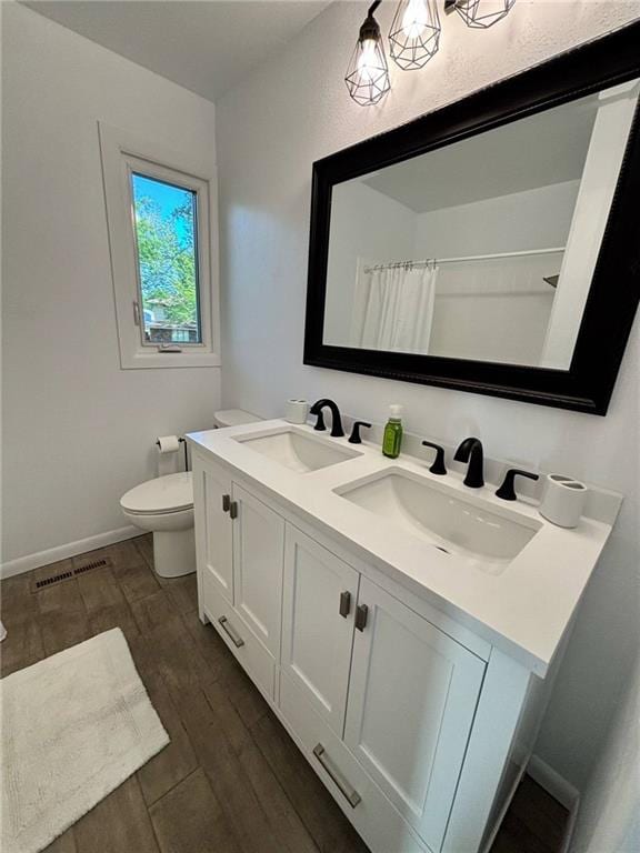 1702 Countryside Dr, Pittsburg, KS 66762 - bathroom with toilet, double vanity, wood finished floors, baseboards, and a shower with shower curtain