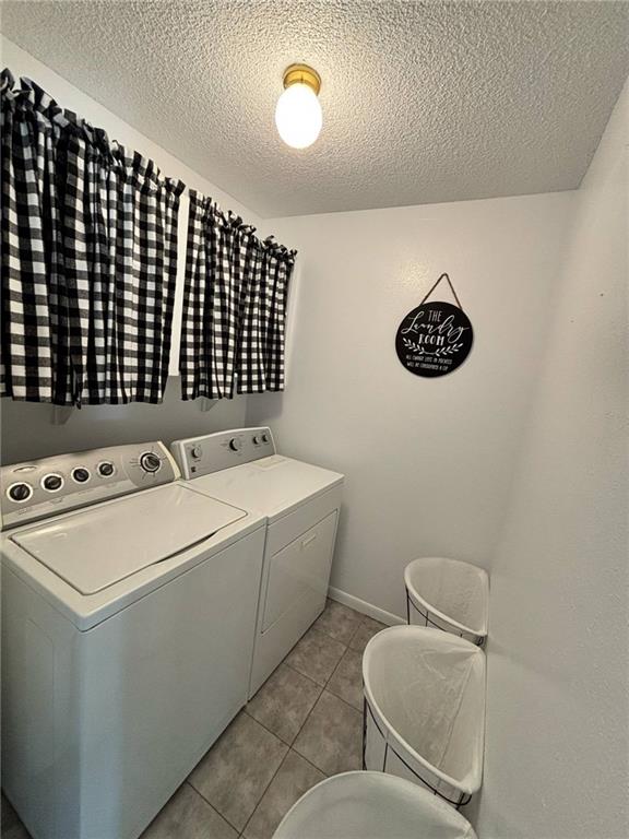 1702 Countryside Dr, Pittsburg, KS 66762 - washroom with independent washer and dryer, a textured ceiling, light tile patterned floors, and baseboards