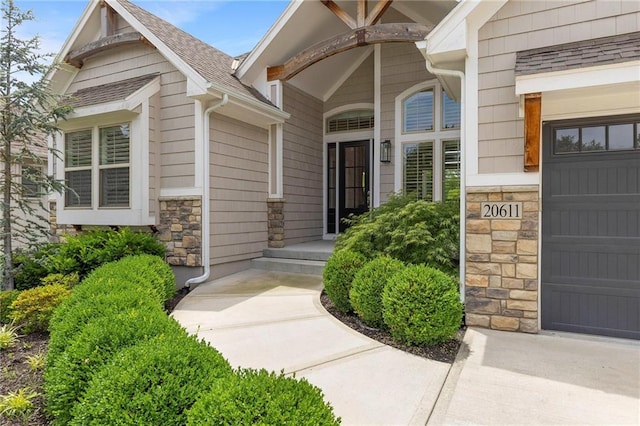 20611 W 113th St, Olathe, KS 66061 - doorway to property with stone siding, an attached garage, and roof with shingles