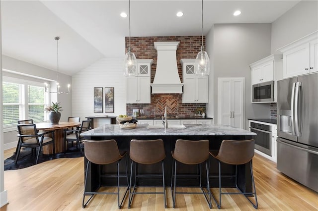 20611 W 113th St, Olathe, KS 66061 - kitchen featuring stainless steel appliances, premium range hood, a kitchen bar, light wood-style flooring, and high vaulted ceiling