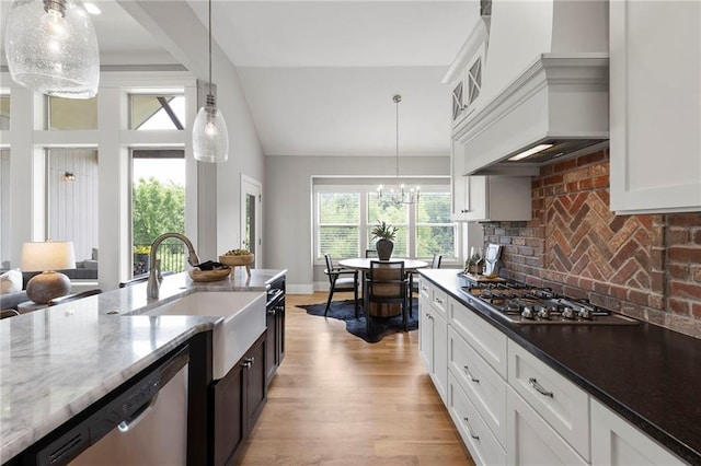 20611 W 113th St, Olathe, KS 66061 - kitchen featuring appliances with stainless steel finishes, custom range hood, light wood-style flooring, light stone counters, and hanging light fixtures