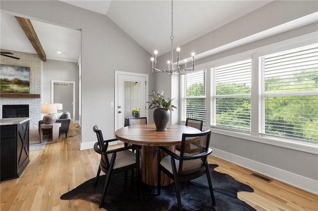 20611 W 113th St, Olathe, KS 66061 - dining space with a large fireplace, lofted ceiling, a chandelier, and light wood-type flooring