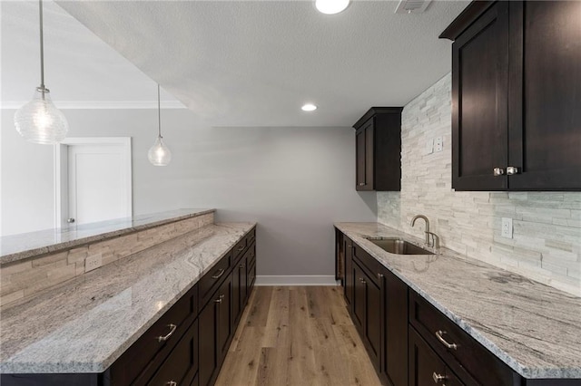 20611 W 113th St, Olathe, KS 66061 - kitchen featuring backsplash, light stone counters, dark brown cabinetry, light wood-style floors, and a textured ceiling
