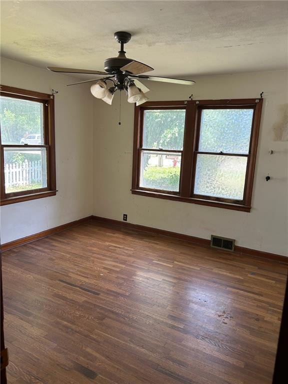 unfurnished room with wood finished floors, a ceiling fan, and baseboards