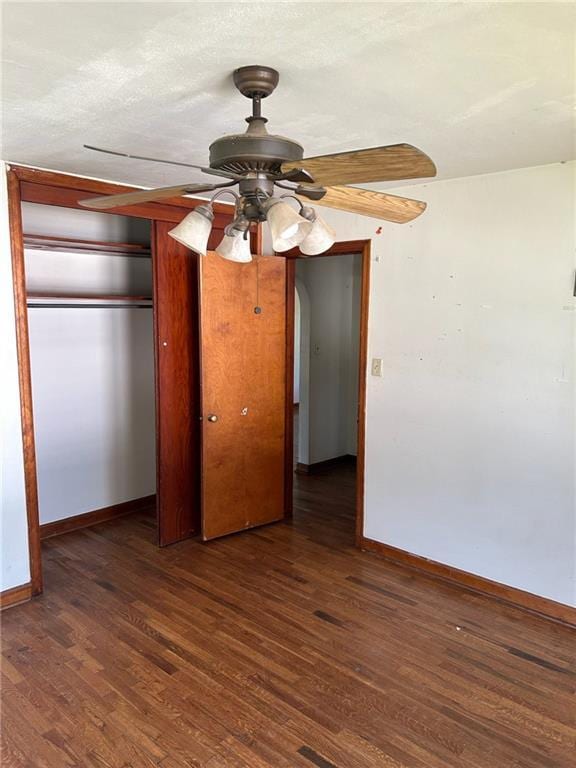 unfurnished bedroom with baseboards, wood finished floors, a closet, and ceiling fan