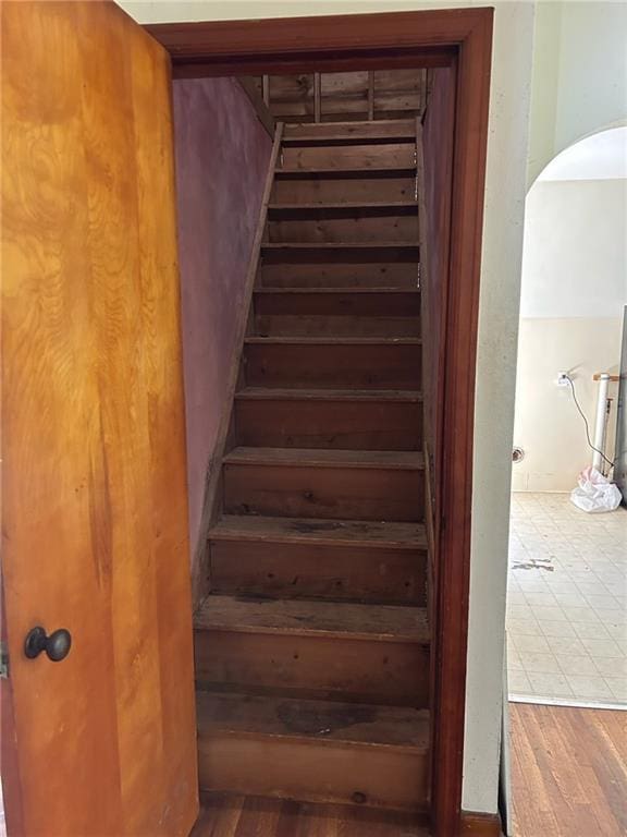 staircase with arched walkways and wood finished floors
