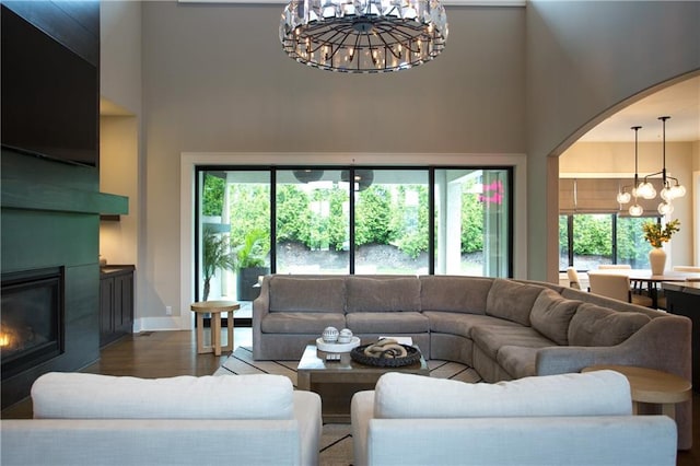 10702 W 142nd Ter, Overland Park, KS 66221 - living area with a towering ceiling, a chandelier, arched walkways, a large fireplace, and healthy amount of natural light