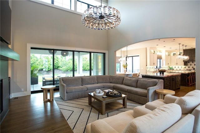 10702 W 142nd Ter, Overland Park, KS 66221 - living room featuring a chandelier, a towering ceiling, plenty of natural light, wood finished floors, and arched walkways