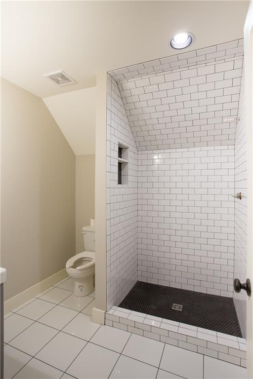 10702 W 142nd Ter, Overland Park, KS 66221 - bathroom with toilet, vaulted ceiling, a shower stall, tile patterned flooring, and baseboards