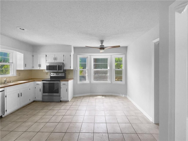 2157 E 154th St, Olathe, KS 66062 - kitchen featuring stainless steel appliances, white cabinetry, healthy amount of natural light, a ceiling fan, and a textured ceiling