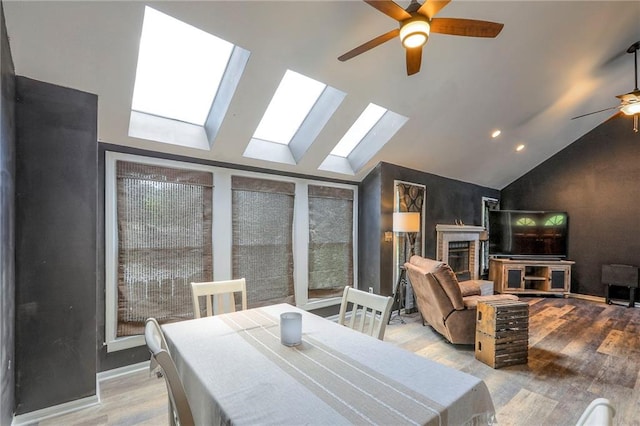 1875 E Mechanic Ave, Independence, MO 64050 - dining room featuring ceiling fan, vaulted ceiling, a skylight, wood finished floors, and a brick fireplace