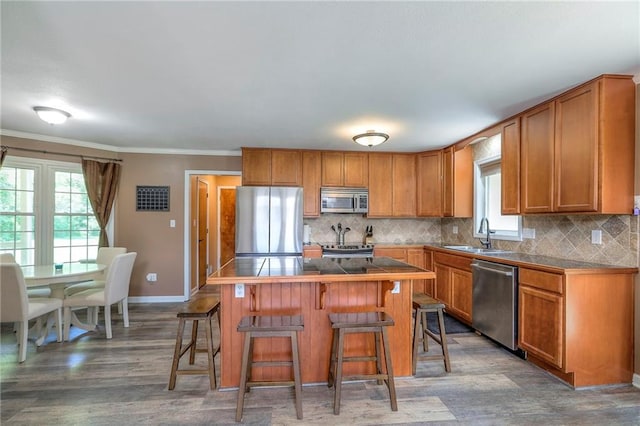 1875 E Mechanic Ave, Independence, MO 64050 - kitchen featuring stainless steel appliances, brown cabinets, a kitchen breakfast bar, wood finished floors, and ornamental molding
