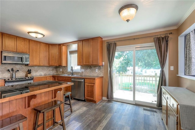 1875 E Mechanic Ave, Independence, MO 64050 - kitchen featuring stainless steel appliances, a kitchen bar, plenty of natural light, dark wood-type flooring, and crown molding