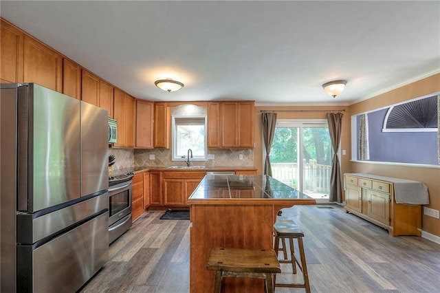 1875 E Mechanic Ave, Independence, MO 64050 - kitchen featuring appliances with stainless steel finishes, dark wood-style floors, backsplash, a center island, and a kitchen breakfast bar