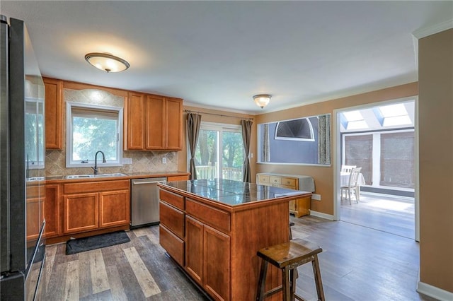 1875 E Mechanic Ave, Independence, MO 64050 - kitchen featuring stainless steel dishwasher, a skylight, dark wood-style flooring, brown cabinets, and tasteful backsplash