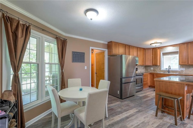 1875 E Mechanic Ave, Independence, MO 64050 - kitchen with stainless steel appliances, tasteful backsplash, wood finished floors, ornamental molding, and a kitchen bar