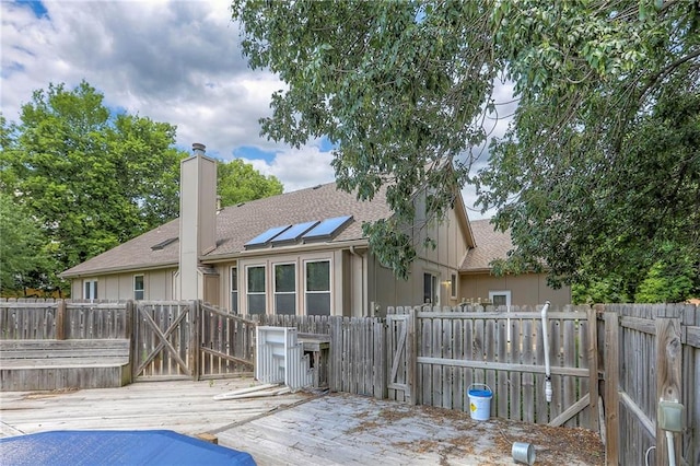 1875 E Mechanic Ave, Independence, MO 64050 - rear view of house with a wooden deck, a shingled roof, a chimney, a fenced backyard, and a gate