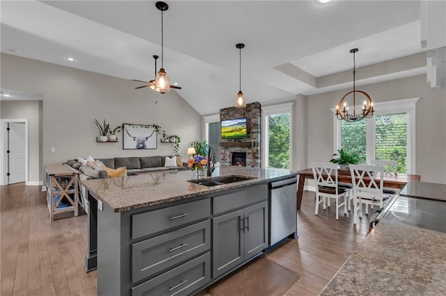 2409 SE Ridge Line Dr, Blue Springs, MO 64014 - kitchen with stainless steel dishwasher, a sink, gray cabinets, a fireplace, and plenty of natural light