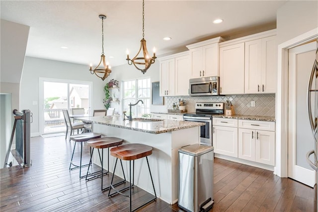 12435 Parkview Ave, Kansas City, KS 66109 - kitchen with appliances with stainless steel finishes, a sink, dark wood-type flooring, a chandelier, and tasteful backsplash