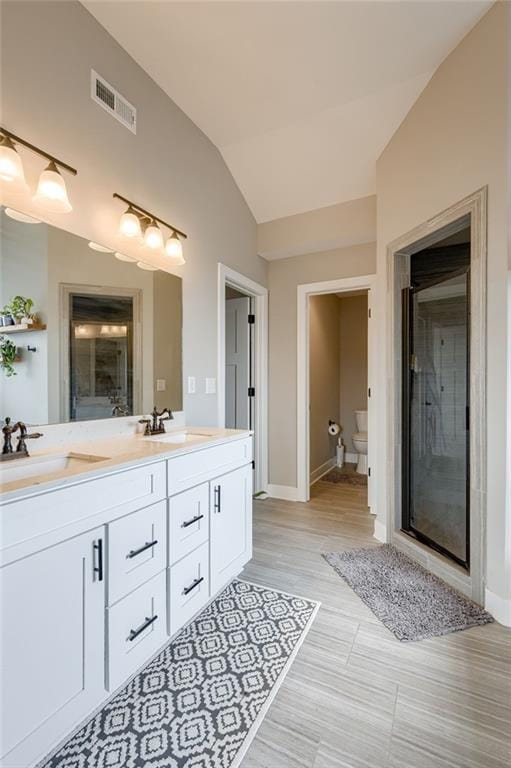 12435 Parkview Ave, Kansas City, KS 66109 - full bath with double vanity, vaulted ceiling, toilet, baseboards, and a shower stall