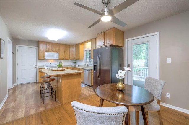 6109 W 54th Ter, Mission, KS 66202 - kitchen featuring appliances with stainless steel finishes, butcher block counters, a textured ceiling, a center island, and light wood-type flooring