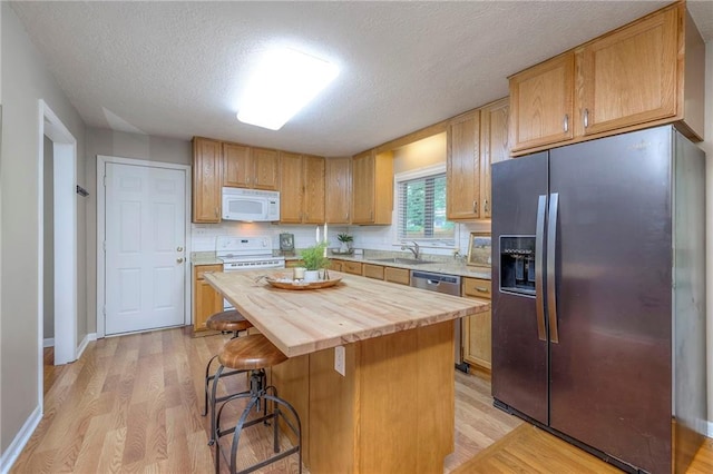 6109 W 54th Ter, Mission, KS 66202 - kitchen with appliances with stainless steel finishes, butcher block counters, a sink, light wood-type flooring, and a textured ceiling