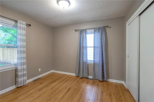 6109 W 54th Ter, Mission, KS 66202 - unfurnished bedroom with light wood-style flooring, multiple windows, a closet, and baseboards