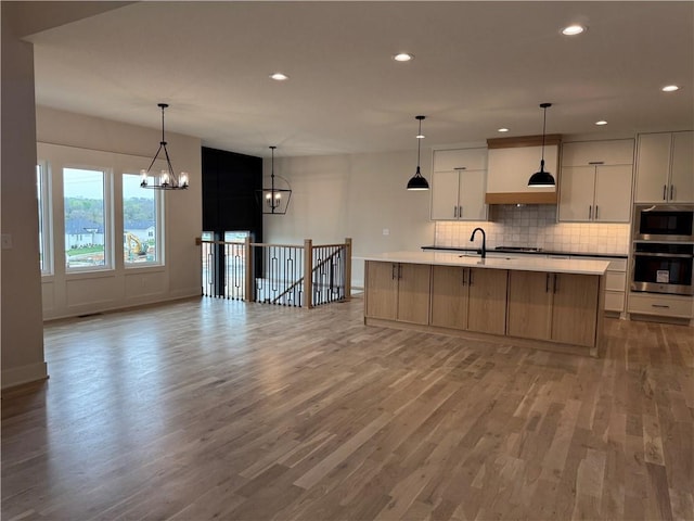 9019 Freedom Cir, Lenexa, KS 66227 - kitchen featuring stainless steel appliances, a chandelier, light wood-style floors, light countertops, and decorative backsplash