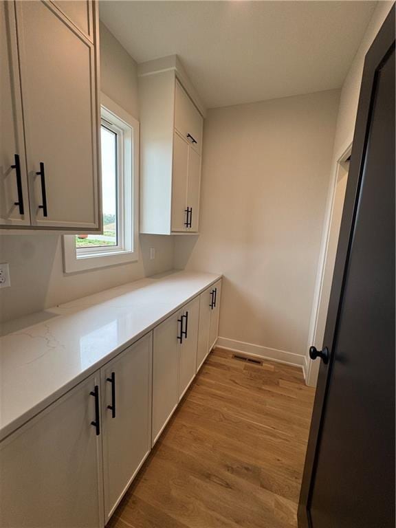 9019 Freedom Cir, Lenexa, KS 66227 - kitchen with light wood finished floors, white cabinetry, baseboards, and light stone countertops