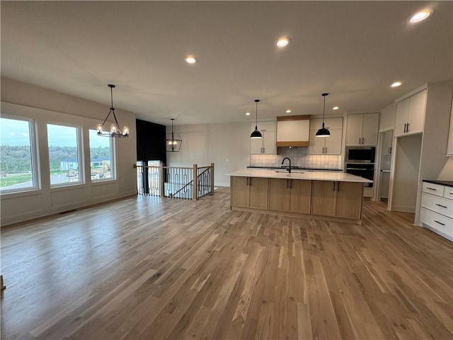 9019 Freedom Cir, Lenexa, KS 66227 - kitchen featuring a chandelier, light wood finished floors, tasteful backsplash, a sink, and recessed lighting